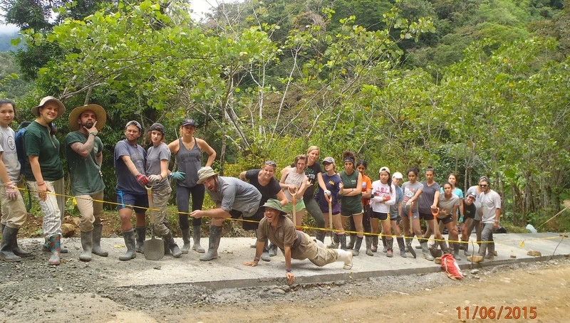 A line of volunteers with shovels standing along a freshly poured concrete path
