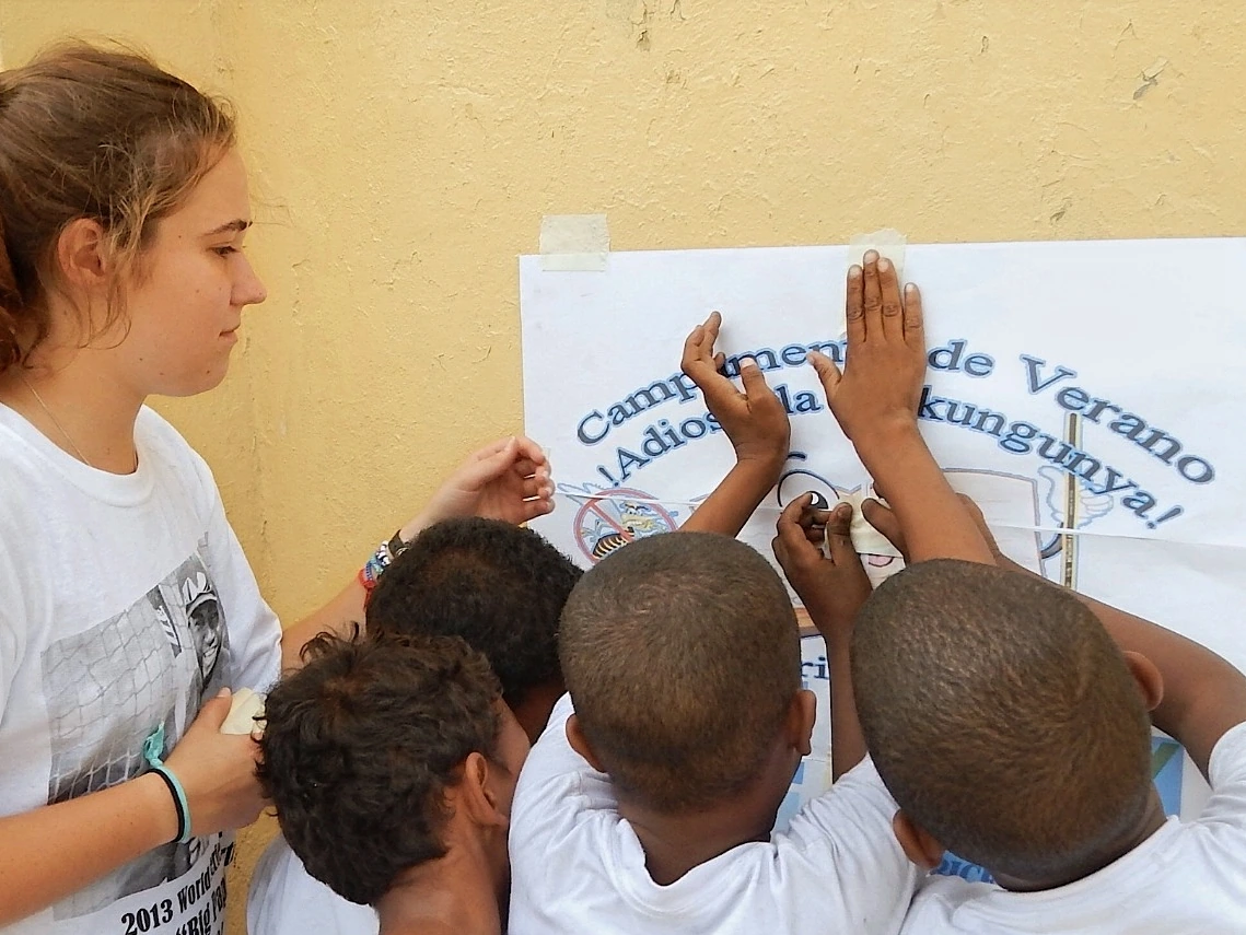 Volunteer and children posting a community health campaign poster